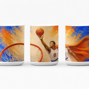 May include: A white ceramic mug featuring a wrap-around artistic print of a basketball player in a white jersey with the number 8, reaching up to shoot a basketball toward a hoop, set against a vibrant blue and orange abstract painted background.