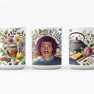 May include: White ceramic mug with a floral design and the text "Hello is it tea you're looking for?"  The mug features a portrait of a man with a mustache and a brown sweater.