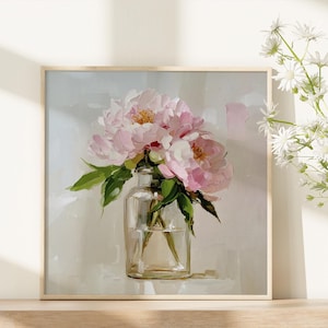 May include: A square framed print featuring a still life of pink peonies in a clear glass vase. The painting has a soft, impressionistic style with visible brushstrokes. Green leaves and white flowers are also visible.