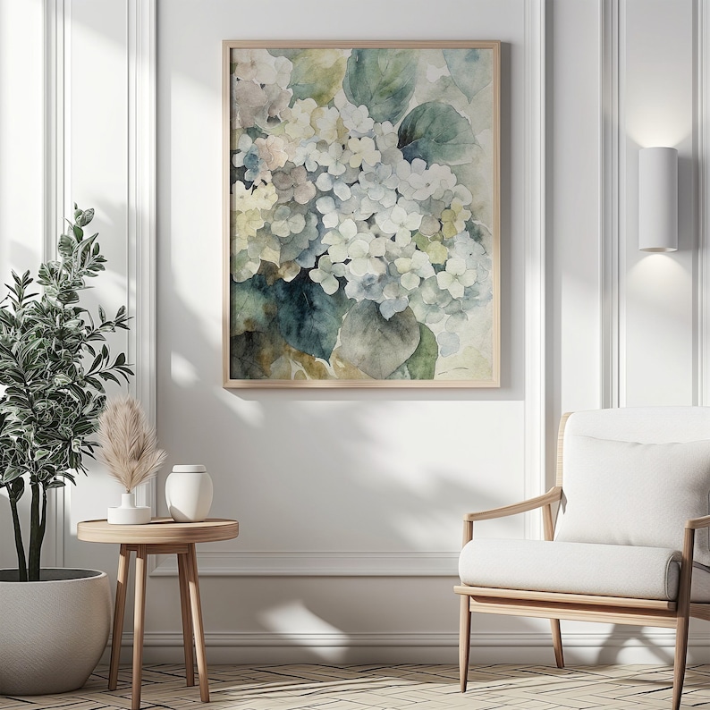 May include: A framed watercolor print featuring a cluster of white and blue hydrangea flowers with green leaves. The artwork has a soft, muted color palette and is displayed in a light wood frame, suitable for home decor.