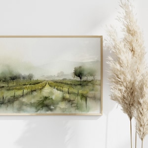 Op de afbeelding: Een aquarel van een mistig landschap met een zandweg die door een veld met bomen en een hek loopt. Het schilderij is ingelijst in een licht houten lijst.