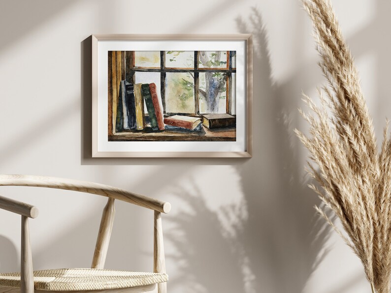 Puede incluir: Una pintura de acuarela de una ventana con libros apilados en el alf&eacute;izar. La ventana est&aacute; enmarcada en madera y tiene una vista de un &aacute;rbol en el exterior. La pintura est&aacute; en un marco de madera claro.