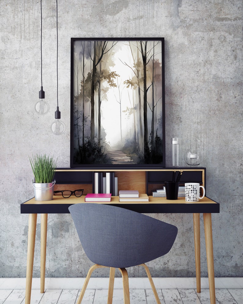 May include: A black framed watercolor painting of a forest path with trees on either side. The painting is hanging on a gray wall above a wooden desk with a black top. There is a gray chair in front of the desk.