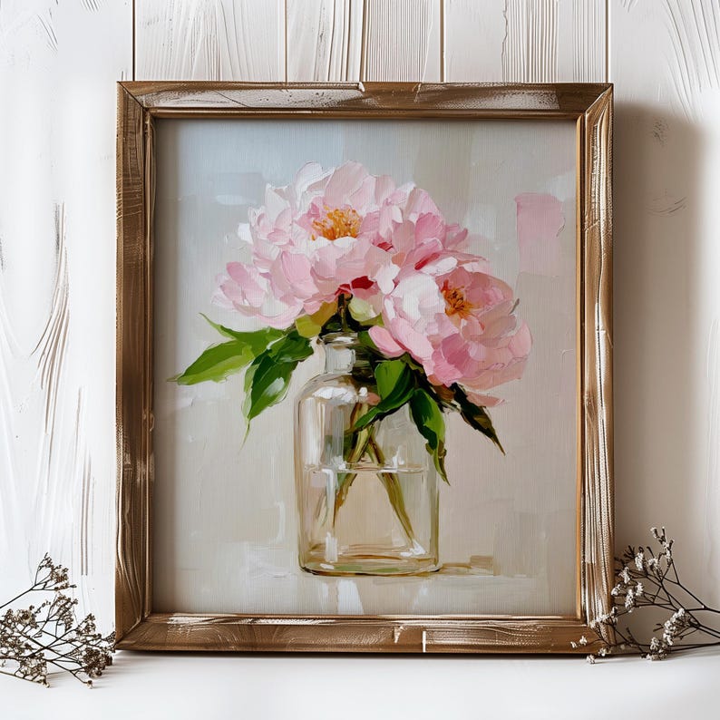 May include: A framed painting of pink peonies in a clear glass vase. The flowers have yellow centers and green leaves. The painting is in a distressed gold-colored wooden frame, set against a light gray background.