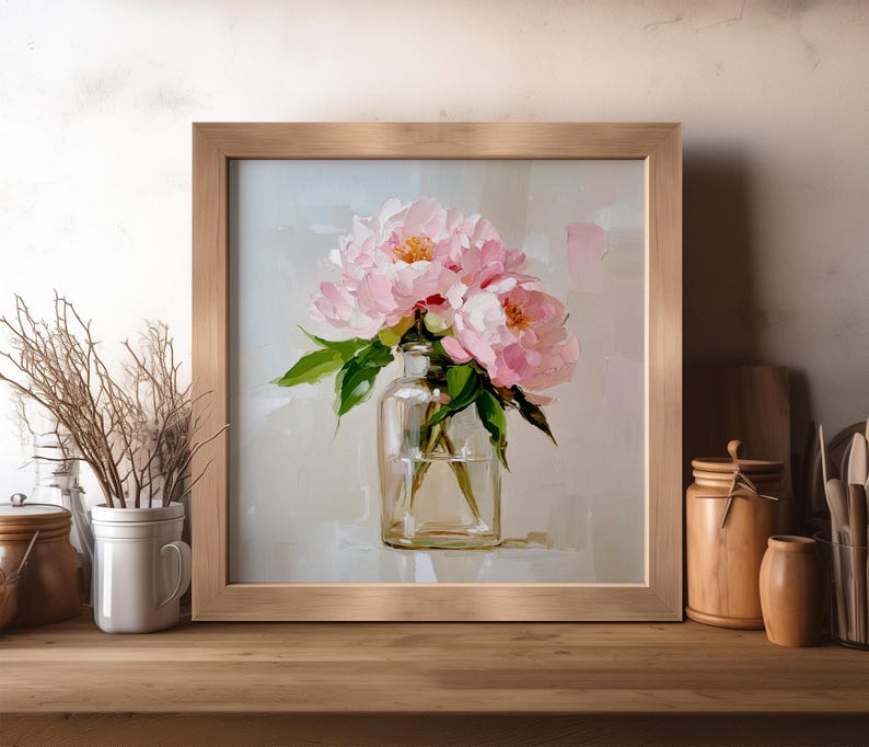 May include: A framed floral painting featuring pink peonies in a clear glass vase. The artwork has a light background and a wooden frame. The painting captures the delicate beauty of the flowers.