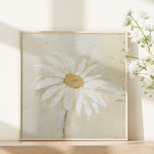May include: A framed painting of a white daisy with a yellow center on a beige background.