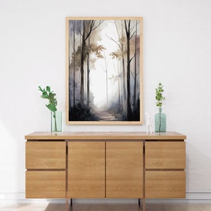 May include: A framed watercolor painting of a misty forest path with tall trees on either side. The painting is in shades of gray, brown, and white, and is framed in a light wood frame.