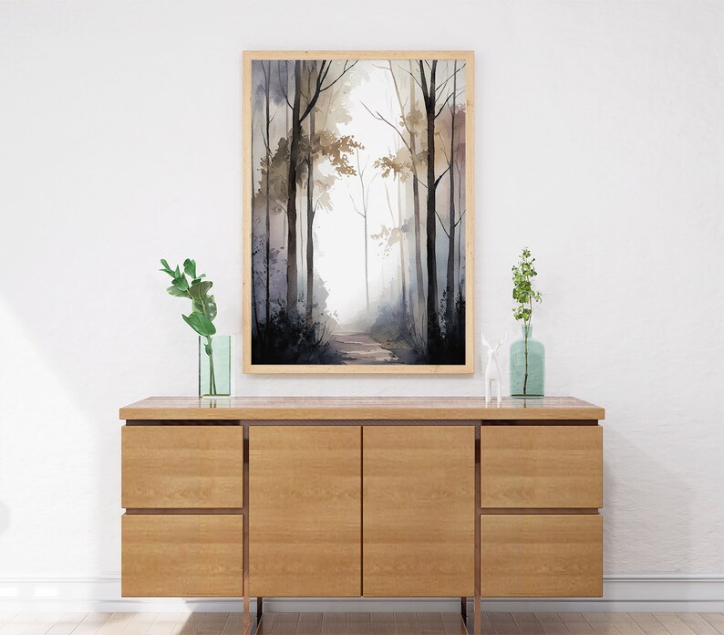 May include: A framed watercolor painting of a misty forest path with tall trees on either side. The painting is in shades of gray, brown, and white, and is framed in a light wood frame.