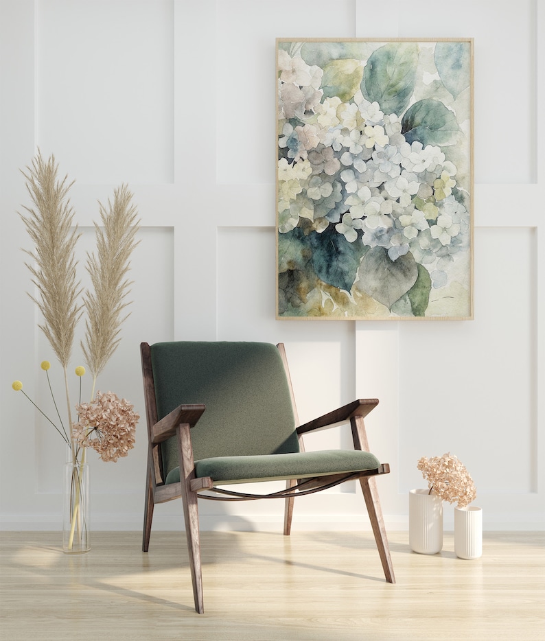 May include: A watercolor painting of white and blue hydrangeas in a wooden frame hangs above a green armchair with wooden arms and legs. Dried flowers and pampas grass are in vases, creating a serene, neutral-toned interior design.