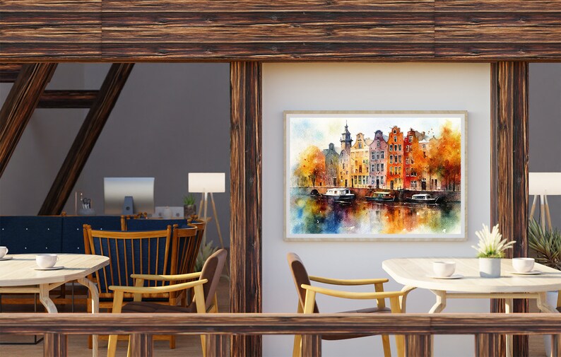 May include: A watercolor painting of a canal scene with colorful buildings and boats. The painting is framed and hanging on a white wall in a room with wooden beams and a table with chairs.