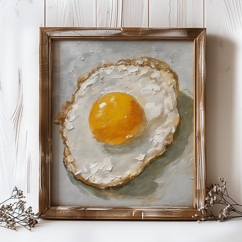 K&ouml;nnte beinhalten: Ein gerahmtes Gem&auml;lde eines Spiegeleis mit einem leuchtend gelben Eigelb. Das Ei ist in einem realistischen Stil mit sichtbaren Pinselstrichen gemalt. Der Rahmen ist ein einfacher Holzrahmen mit einer abgenutzten Oberfl&auml;che.