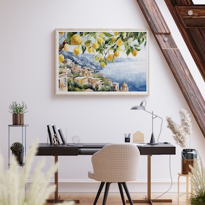 May include: A watercolor painting of a lemon tree with yellow lemons hanging from the branches. The tree is in front of a view of a coastal town with buildings and a blue sea. The painting is framed in a light wood frame.