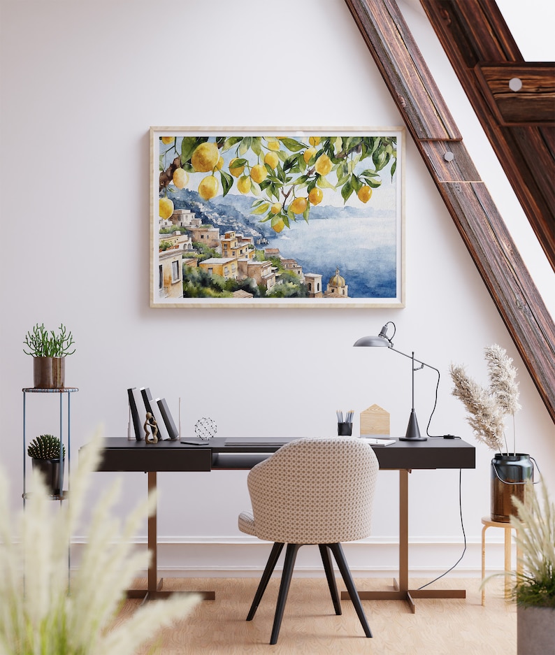 May include: A watercolor painting of a lemon tree with yellow lemons hanging from the branches. The tree is in front of a view of a coastal town with buildings and a blue sea. The painting is framed in a light wood frame.