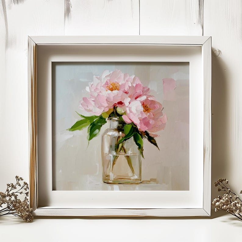 May include: A framed painting of pink peonies in a clear glass vase. The artwork features a soft, impressionistic style with visible brushstrokes. The flowers have yellow centers and green leaves, set against a neutral background.