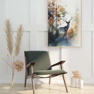 May include: A green velvet armchair with wooden legs sits in a room with white walls and a watercolor painting of a deer in a forest. The painting is framed in a light wood frame.