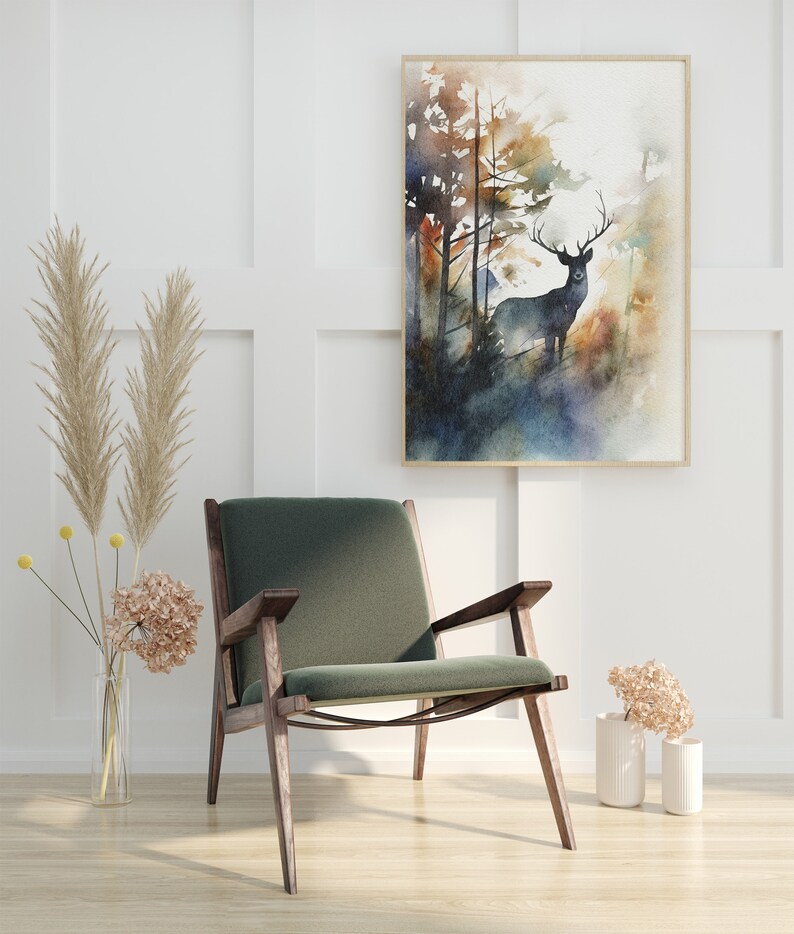 May include: A green velvet armchair with wooden legs sits in a room with white walls and a watercolor painting of a deer in a forest. The painting is framed in a light wood frame.