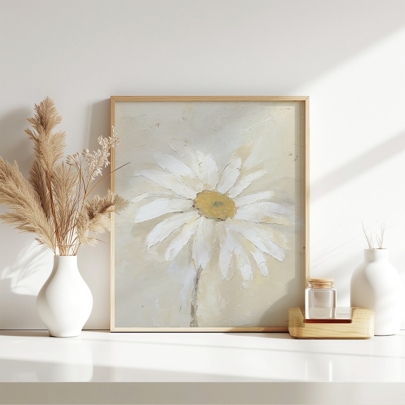 May include: A framed painting of a white daisy with a yellow center on a beige background.