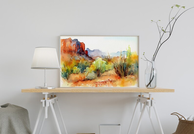 Puede incluir: Pintura acuarela de un paisaje des&eacute;rtico con formaciones rocosas rojas, arbustos verdes y un cielo azul. La pintura est&aacute; enmarcada y colgada en una pared blanca.
