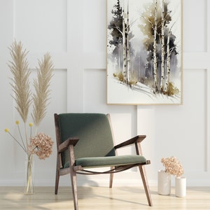 May include: A green velvet armchair with dark wood legs sits in a room with white walls and a framed watercolor painting of trees. The painting features a light brown and gray color scheme with a hint of green. Two dried flower arrangements are on the floor.