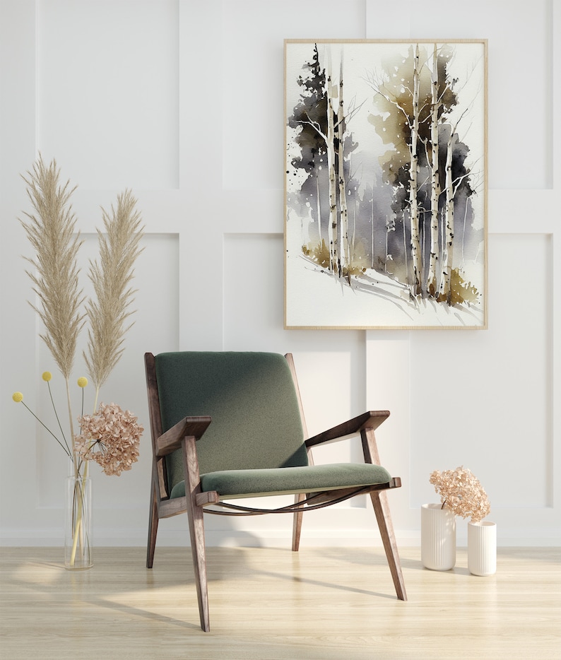 May include: A green velvet armchair with dark wood legs sits in a room with white walls and a framed watercolor painting of trees. The painting features a light brown and gray color scheme with a hint of green. Two dried flower arrangements are on the floor.
