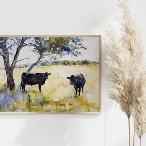 May include: Watercolour painting of two black cows standing in a field with a tree in the background. The cows are facing different directions and the field is a mix of green and yellow.