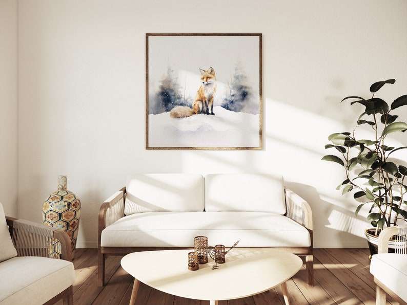 May include: A watercolor painting of a red fox sitting in a snowy forest. The painting is framed in a light wood frame and is hanging on a white wall in a living room setting.