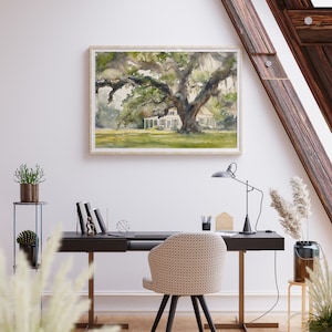 May include: A watercolor painting of a white house with a large oak tree in front of it. The house has a porch and a roof with a slight curve. The tree has many branches and leaves. The painting is framed in a light wood frame.