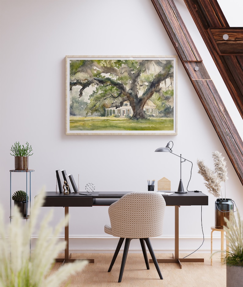 May include: A watercolor painting of a white house with a large oak tree in front of it. The house has a porch and a roof with a slight curve. The tree has many branches and leaves. The painting is framed in a light wood frame.