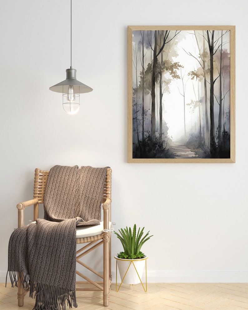 May include: A brown wicker chair with a brown throw blanket draped over it. A white planter with a green succulent plant sits on a gold metal stand. A framed watercolor painting of a forest path hangs on the wall above the chair.