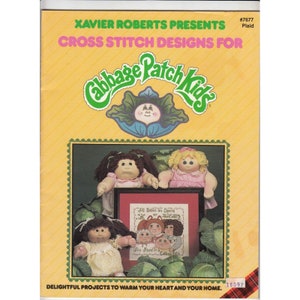 May include: Cross stitch pattern booklet featuring Cabbage Patch Kids. The cover shows three Cabbage Patch Kids dolls and a cross stitch design with the text "All Babies are Special, We Found in a Cabbage Patch".