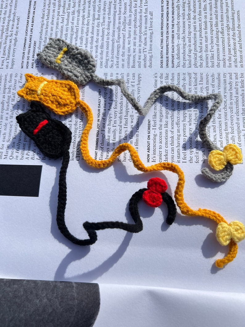 May include: A collection of crocheted animal figures in various colors, including black, red, yellow, and gray. The figures are arranged on a white surface with text in the background.