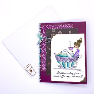 May include: Greeting card with a watercolor illustration of a woman relaxing in a teacup, holding a small cup. The card has a purple and white patterned background, with the text "Sometimes they just make coffee cups too small."