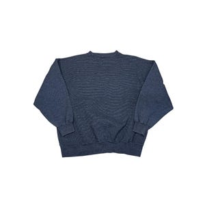 May include: A dark blue sweatshirt with long sleeves. The sweatshirt is made of a soft material and has a crew neck. The sleeves have ribbed cuffs. The garment is laid flat on a white surface.
