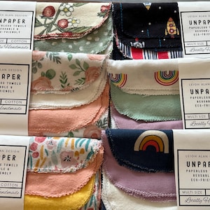 May include: A collection of multi-size, cotton, reusable, and eco-friendly paperless towels. The towels feature various patterns, including floral, rainbows, and rockets. The packaging reads "UNPAPER" and "Locally Handmade."