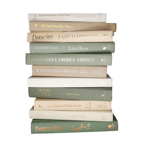 May include: A vertical stack of eleven hardcover books featuring a color palette of sage green, cream, and beige. The spines display various titles and author names in gold foil lettering, including Conversations with God, Safe Harbour, and Bungalow 2.