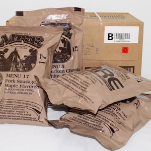 May include: An assortment of MRE (Meal, Ready-to-Eat) food pouches and a cardboard box. The pouches are tan with black text and illustrations, featuring various menu items like pork sausage and chicken chunks. The box has a white label with a barcode.