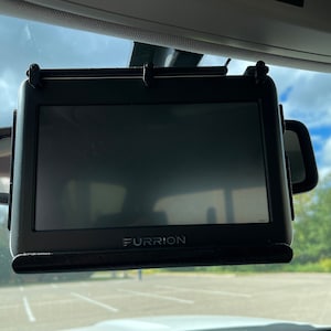 May include: A black Furrion brand rearview mirror monitor mounted to the inside of a car windshield.