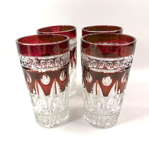 以下が含まれることがあります： 赤いカットガラスのデザインが施された透明なガラスのタンブラー4個セット。タンブラーは幅広の底とストレートな円筒形をしています。