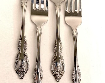 May include: Four silver forks with ornate handles. The forks have a traditional design with a floral pattern.