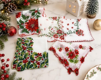 May include: A collection of five square fabric napkins featuring festive holiday prints. The designs include red poinsettias, green holly leaves with red berries, and delicate white fabric with scalloped edges in red and green thread.