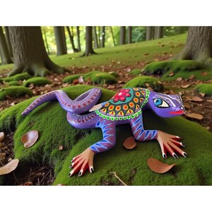 May include: A handcrafted, colorful wooden lizard figurine with a purple body, patterned tail, and human-like hands. The lizard has a decorative floral design on its back and is set against a mossy green background.