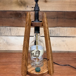 May include: A table lamp made from a repurposed Buffalo Trace bourbon bottle, with a wooden base and a black metal lampshade.