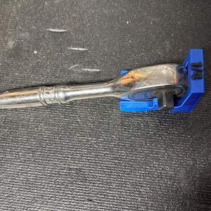 Puede incluir: Una llave de carraca plateada con un soporte azul de 1/4 de pulgada. La llave est&aacute; sobre una superficie negra texturizada. El soporte azul tiene el n&uacute;mero "1/4" impreso.