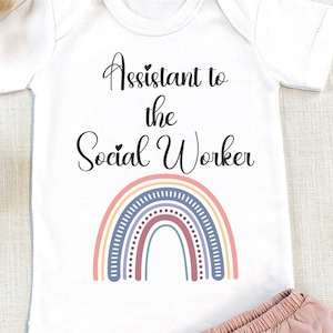 May include: White baby onesie with a rainbow and the text "Assistant to the Social Worker".