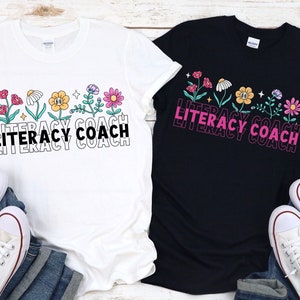 May include: Two t-shirts with a floral design and the text "Literacy Coach" in black and pink. The shirts are white and black.