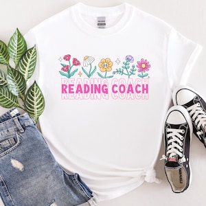 May include: White t-shirt with a pink "Reading Coach" graphic and a row of colorful flowers with smiling faces.