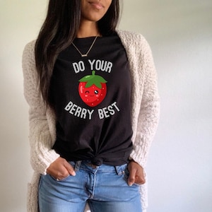 May include: Black t-shirt with a white graphic of a red strawberry with a smiling face and the text "Do your berry best".
