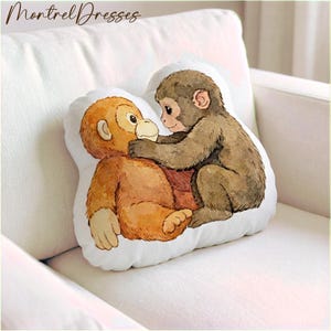 May include: A white, cloud-shaped pillow featuring a watercolor illustration of two monkeys. One monkey is brown, and the other is orange. The text "Montrel Dresses" is in the upper left corner.
