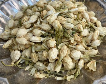 May include: A silver bowl filled with dried jasmine flower buds. The buds are a pale cream color and have a delicate, floral scent.