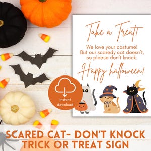 Op de afbeelding: Printbare Halloween-bord met een witte achtergrond en kleurrijke illustraties van katten. Het bord luidt "Neem een traktatie! We houden van je kostuum! Maar onze schuwe kat vindt het niet leuk, dus kloppen is niet gewenst. Gelukkig Halloween!"
